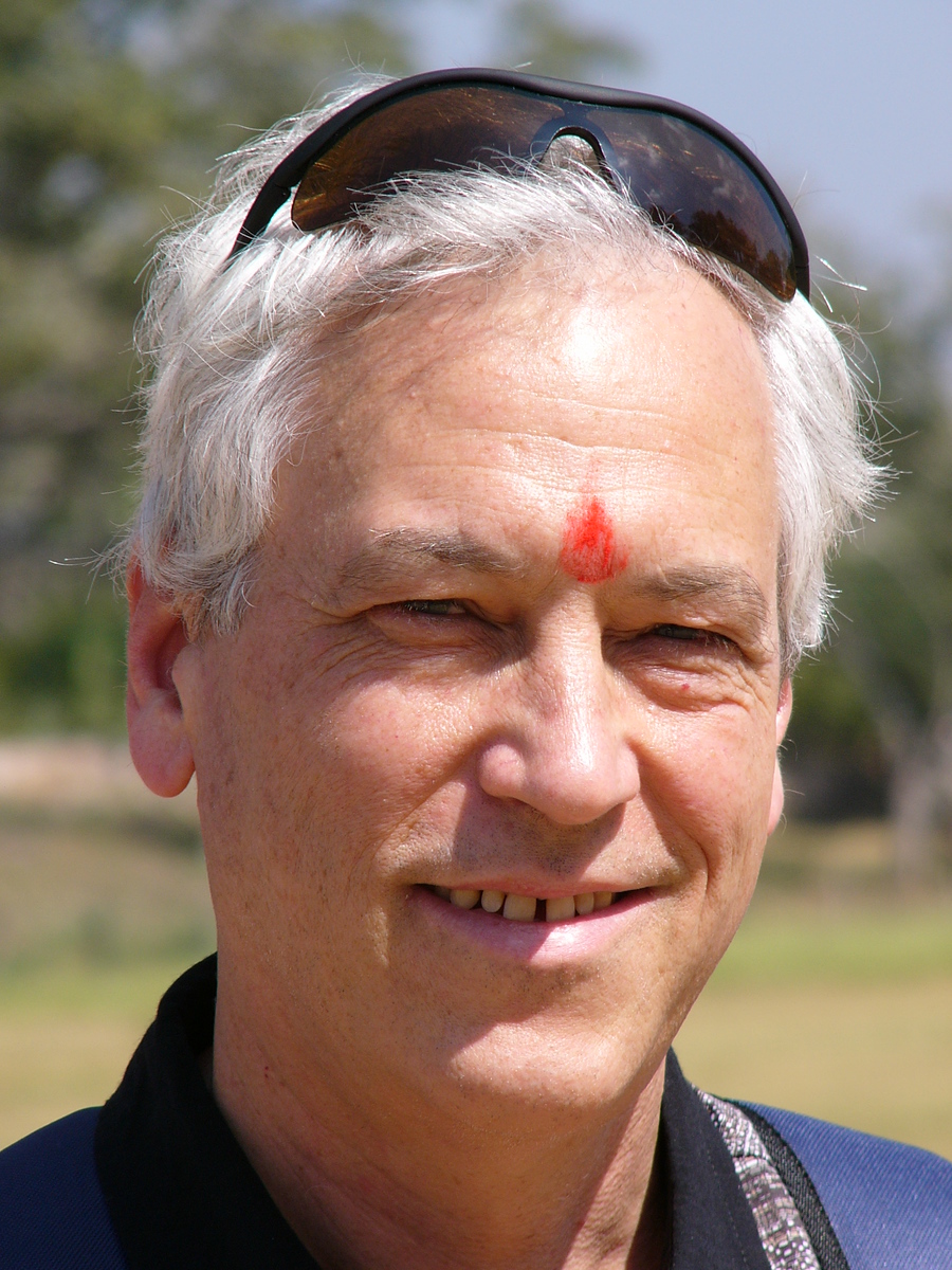 Evans Harrell outdoors in India, sunglasses pushed up on his head, a red tilak on his forehead