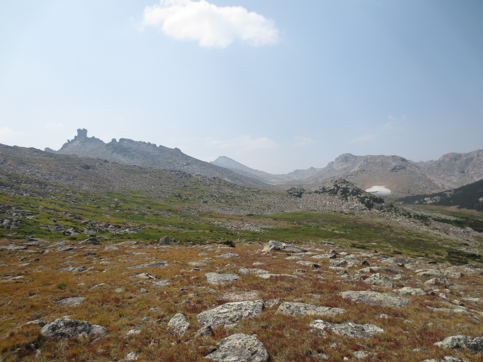 A hiker resting beside a pack on bare rock at high altitude