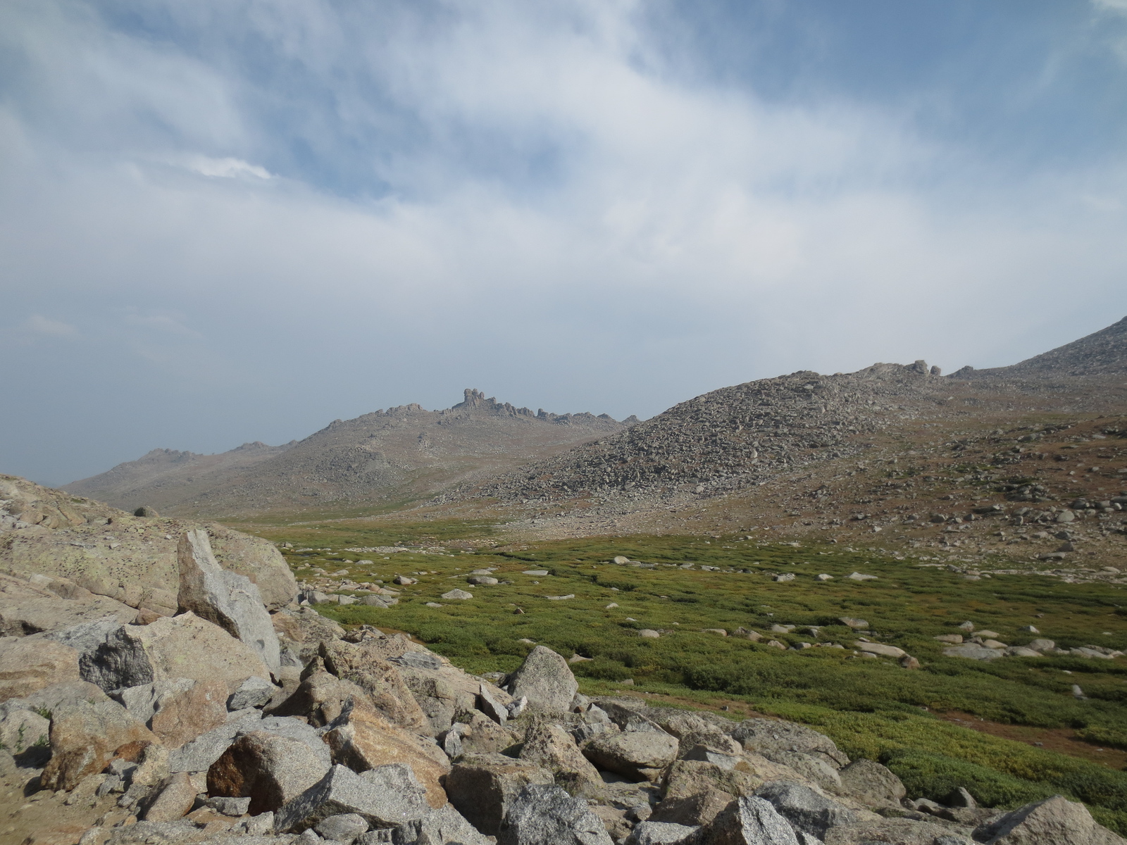 Open alpine tundra and boulder fields under a wide cloudy sky